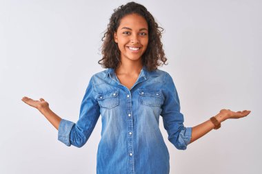 Genç Brezilyalı kadın iki el açık avuç içi gösteren gülümseyen izole beyaz arka plan üzerinde ayakta denim gömlek giyen, sunma ve reklam karşılaştırma ve denge