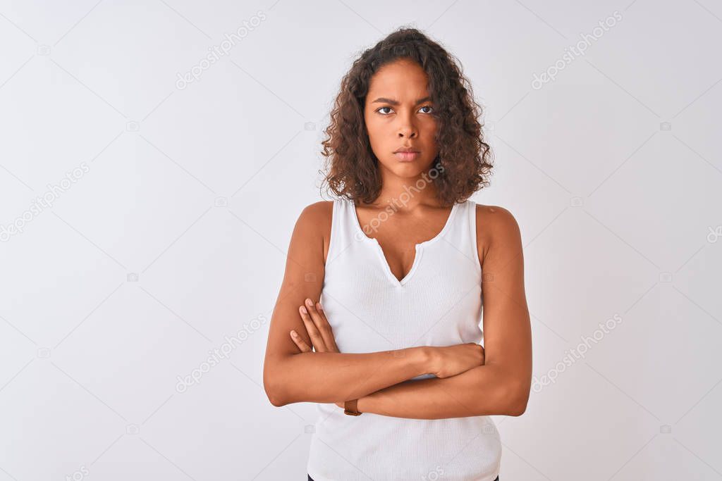 Young brazilian woman wearing casual t-shirt standing over isolated white background skeptic and nervous, disapproving expression on face with crossed arms. Negative person.