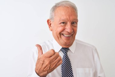 Üst düzey gri saçlı işadamı izole beyaz arka plan üzerinde duran kravat giyen işaret ve mutlu yüzü gülümseyerek yan başparmak ile gösteren