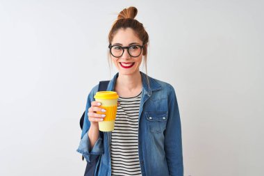 Güzel Redhead öğrenci kadın içme mutlu bir yüz ayakta ve emin bir gülümseme dişleri gösteren ile gülümseyen izole beyaz arka plan üzerinden kahve almak