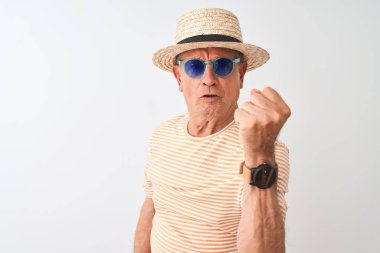 Izole beyaz arka plan üzerinde çizgili t-shirt güneş gözlüğü ve sümer şapka giyen Kıdemli adam kızgın ve sinirli öfke, deli ve yükseltilmiş el, öfke kavramı ile bağırarak sinirli