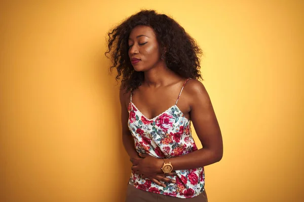 アフリカ系アメリカ人女性は 吐き気 痛みを伴う病気の気分が悪いので 胃の上に孤立した黄色の背景の上に花の夏のTシャツを着ています 痛い概念 — ストック写真