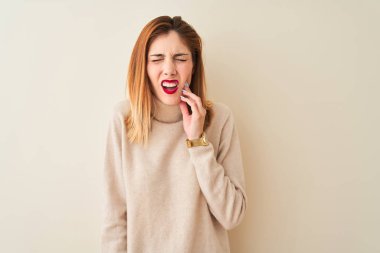 Kızıl saçlı kadın diş ağrısı veya diş hastalığı nedeniyle ağrılı ifade ile el ağız dokunmadan izole beyaz arka planda ayakta zarif balıkçı yaka kazak giyiyor. Dişçi konsepti.