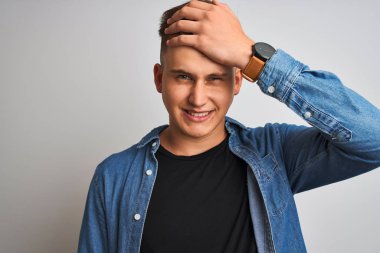İzole beyaz arka plan üzerinde duran denim gömlek giyen genç yakışıklı adam baş el ile vurguladı, utanç ve sürpriz yüz ile şok, kızgın ve sinirli. Korku ve hata için üzgün.