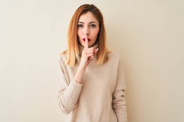 Kırmızı kadın dudaklar üzerinde parmak ile sessiz olmak isteyen izole beyaz arka plan üzerinde ayakta zarif balıkçı yaka kazak giyiyor. Sessizlik ve gizli konsept.