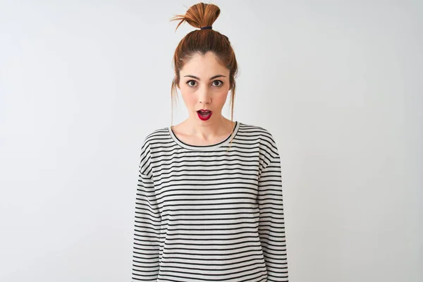 Redhead woman wearing navy striped t-shirt standing over isolated white background afraid and shocked with surprise expression, fear and excited face.