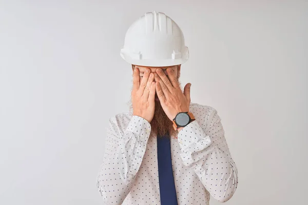 年轻的红发爱尔兰建筑师男子戴着安全帽在孤立的白色背景与悲伤的表情覆盖脸与双手 而哭泣 抑郁症概念 — 图库照片