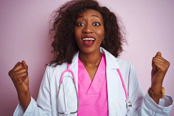 African american doctor woman wearing stethoscope over isolated pink background celebrating surprised and amazed for success with arms raised and open eyes. Winner concept.
