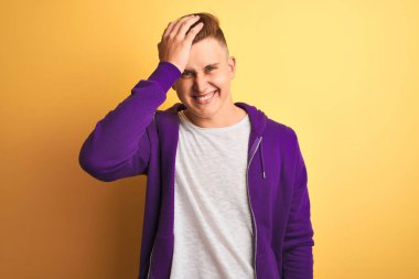 Mor sweatshirt giyen genç yakışıklı adam izole sarı arka plan üzerinde duran hata için kafasına el ile şaşırttı, hata hatırlıyorum. Unuttum, kötü bellek kavramı.