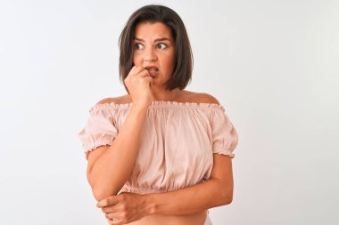 Genç güzel kadın rahat t-shirt izole beyaz arka plan üzerinde duran giyen stresli ve ağız tırnak ısırma elleri ile sinir görünümlü. Anksiyete sorunu.