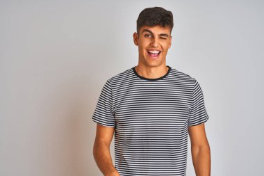 Izole beyaz arka plan üzerinde duran lacivert çizgili t-shirt giyen genç hintli adam seksi ifade, neşeli ve mutlu yüz ile kameraya bakarak göz kırpıyor.