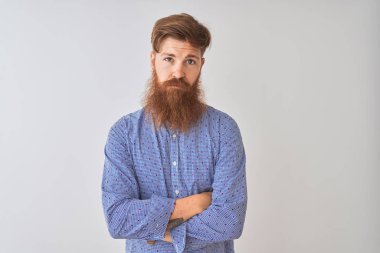 İzole beyaz arka plan üzerinde ayakta sıradan gömlek giyen genç Kızıl İrlandalı adam şüpheci ve sinir, Çapraz kollar ile yüz üzerinde ifade onaylamıyor. Negatif kişi.