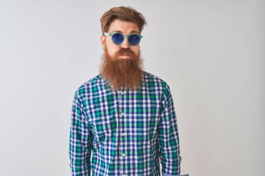 Komik yüz ile izole beyaz arka plan kabarık yanakları üzerinde rahat gömlek ve güneş gözlüğü giyen genç Redhead İrlandalı adam. Ağız hava ile şişirilmiş, çılgın ifade.