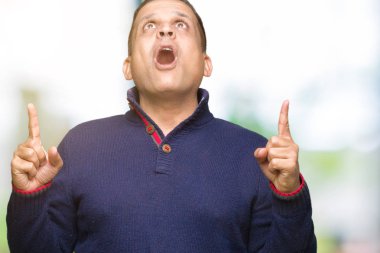 Orta yaş Arap adam izole arka plan üzerinden hayran ve yukarıya bakıp parmakları ile işaret şaşırttı ve silah kaldırdı.