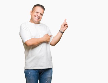Kameraya bakarak yan el ve parmak ile işaret yüzünde kocaman bir gülümseme ile arka plan beyaz t-shirt üzerine izole orta yaş Arap adam wearig.