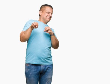 Orta yaş Arap adam izole arka plan üzerinde mavi t-shirt giyen tiksinti ifadesi, memnun ve korkulu tiksinti yüz yapıyorsun çünkü nefret tepki. Elleriyle kaldırdı. Sinir bozucu kavramı.