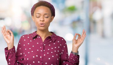 İzole arka plan üzerinde kafa eşarp giyen güzel genç Afrikalı Amerikan kadın rahatlayın ve gözleri ile gülümseyen meditasyon jest parmaklar ile kapalı. Yoga konsepti.