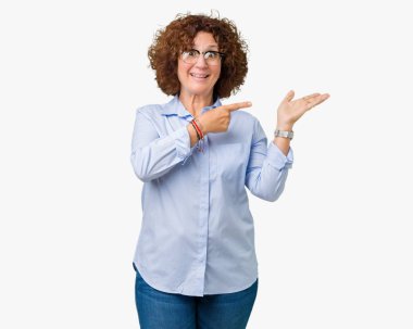 Hayret ve el ile sunulması ve parmak ile işaret ederken kameraya gülümseyen izole arka plan üzerinde gözlük güzel orta ager üst düzey businees kadın.