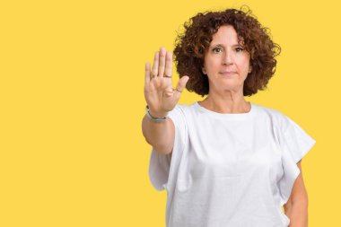 Beyaz giyen güzel orta ager üst düzey kadın t-shirt dur yapıyor izole arka plan üzerine şarkı elin avuç ile. Negatif ve ciddi bir jest yüz ifadesiyle uyarı.