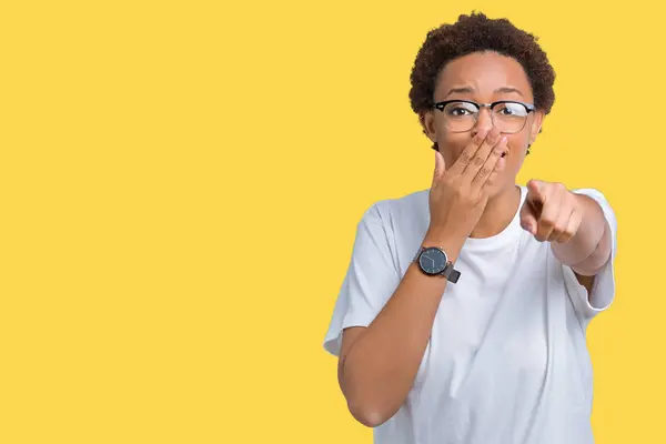 美しい若いアフリカ系アメリカ人女性分離で眼鏡をかけて背景恥式口に指の手でカメラを指しているあなたの笑い — ストック写真