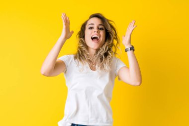 Güzel genç sarışın kadın mutlu ve izole sarı arka plan üzerinde atlama