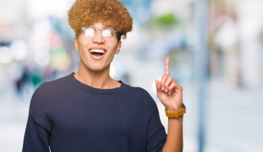 Afro giyen ile genç yakışıklı adam başarılı fikirle işaret parmağı gözlük. Çıktıktan ve mutlu. Bir numara.