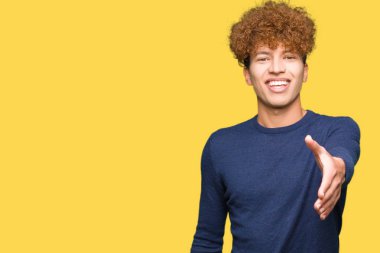 Afro saç ile genç yakışıklı adam tebrik ve davetkar olarak dostu sunan el sıkışması gülümseyen. Başarılı iş.