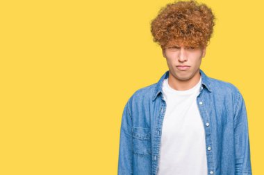 Afro saç ile genç yakışıklı adam denim ceket şüpheci ve sinir giyen, sorun nedeniyle üzgün çatık. Negatif kişi.