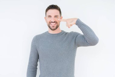 İzole arka planda rahat kazak giyen genç yakışıklı adam yüz ve burun, neşeli gülümseyen el parmak ile Işaret