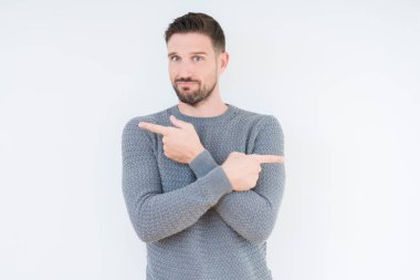 İzole arka planda rahat kazak giyen genç yakışıklı adam parmaklarla her iki tarafa Işaret, farklı yönde katılmıyorum