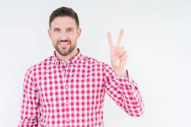 İzole arka plan üzerinde gömlek giyen genç yakışıklı adam gösteren ve parmaklar iki numarası ile işaret kadar emin ve mutlu gülümseyen.