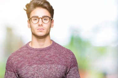 Üzerinde gözlük takan genç yakışıklı adam arka plan gevşek yüzünde ciddi bir ifade ile izole. Basit ve doğal kameraya bakıyor.