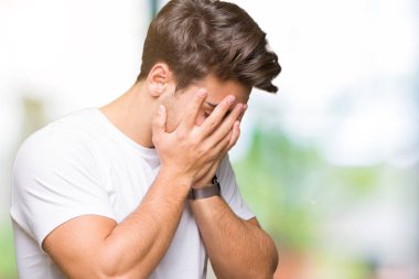 Yüzünü elleriyle ağlayarak süre kapsayan üzgün ifade ile izole arka plan üzerinde beyaz t-shirt giyen genç yakışıklı adam. Depresyon kavramı.