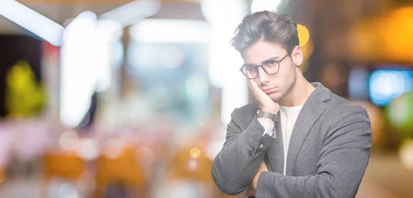 Young business man wearing glasses over isolated background thinking looking tired and bored with depression problems with crossed arms.