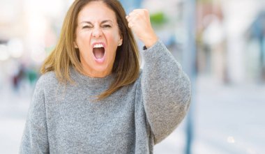 Üzerinde kış kazak giyen güzel orta yaş kadın arka plan kızgın izole ve kızgın yetiştirme hayal kırıklığı ve öfke ile bağırarak süre öfkeli yumruk. Öfke ve agresif kavramı.