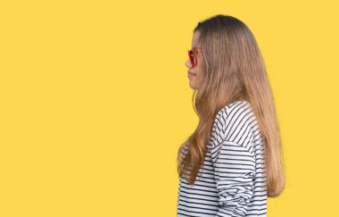 Çizgili süveter ve kırmızı gözlük izole arka tarafına, seyir üzerinde giyen genç güzel esmer kadın dinlenmek doğal yüz emin gülümseme ile pozuyla profili.