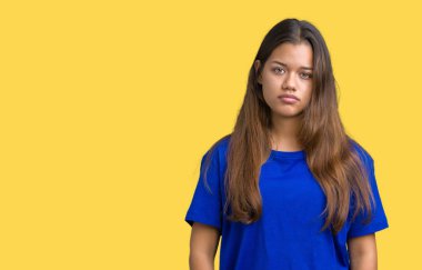 Üzerinde mavi t-shirt giyen genç güzel esmer kadın arka plan gevşek yüzünde ciddi bir ifade ile izole. Basit ve doğal kameraya bakıyor.