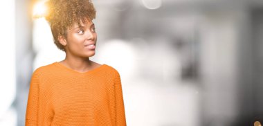 Güzel genç Afro-Amerikan kadın uzak tarafına yüzünde, doğal ifade gülümseme ile seyir izole arka plan yüzünden. Kendine güvenen gülüyor.