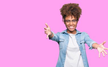 Sarılmak için kollarını açarak gülümseyerek kameraya bakarak izole arka plan üzerinde gözlük güzel genç Afro-Amerikan kadın. Neşeli ifade kucaklayan mutluluk.