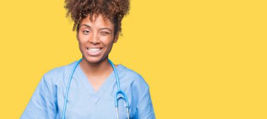 Genç Afro-Amerikan doktor kadın seksi bir ifadeyle, neşeli ve mutlu yüzünü kameraya bakarak göz kırpıyor izole arka plan.