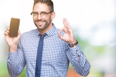 Genç iş adamı gösteren smartphone ekran parmak, mükemmel sembolü ile ok işareti yapıyor izole arka plan üzerinde