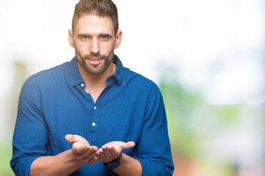 Yakışıklı delikanlı izole arka plan üzerinde gülen ellerle birlikte alma veya jest vererek palms. Ayrı tutma ve koruma