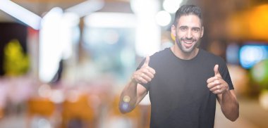 Yakışıklı delikanlı izole arka plan başarı işareti el ile pozitif jest yapıyor üzerinde başparmak gülümseyen ve mutlu. Neşeli bir ifadeyle, kazanan jest kameraya bakıyor.