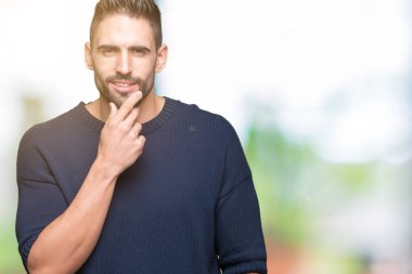 Emin çapraz kollar ve çeneme kaldırdı el ile gülümseme ile kameraya bakarak izole arka plan üzerinde kazak giyen genç yakışıklı adam. Pozitif düşünce.