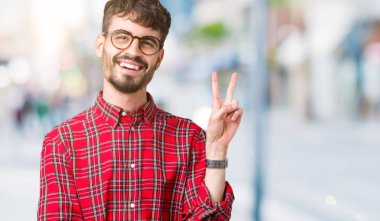 Mutlu yüz zafer işareti yaparken kameraya göz kırpıyor ile gülümseyen izole arka plan üzerinde gözlük takan yakışıklı delikanlı. İki numaralı.