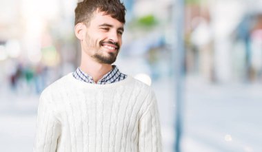 Üzerinde kış kazak giyen genç yakışıklı adam arka plan uzak tarafına gülümseme ile yüzünde, doğal ifade arıyorum izole. Kendine güvenen gülüyor.