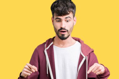 İzole genç yakışıklı adam arka plan işaretleme aşağı reklam, sürpriz yüz ve açık ağız gösterilen parmakları ile