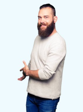 Açık el ile doğal gülümseyen girmek için rahat kazak davet giyen genç sarışın adam