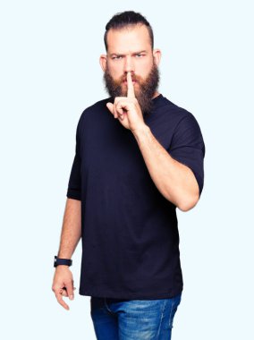 Genç Sarışın dudaklarında parmak ile sessiz olmanı giyiyor rahat t-shirt adam. Sessizlik ve gizli kavramı.