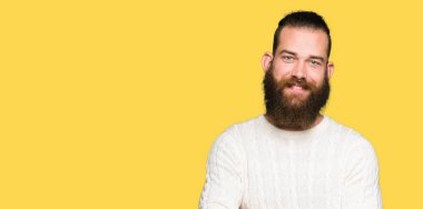 Genç hipster adam, kamera bakarak çapraz silah ile gülümseyen kış kazak mutlu yüz giyiyor. Pozitif kişi.